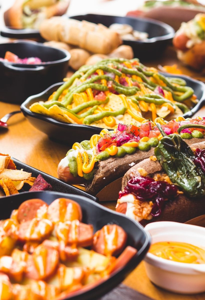 Close-up of plate with nacho chips in dressing served with various snacks on table.